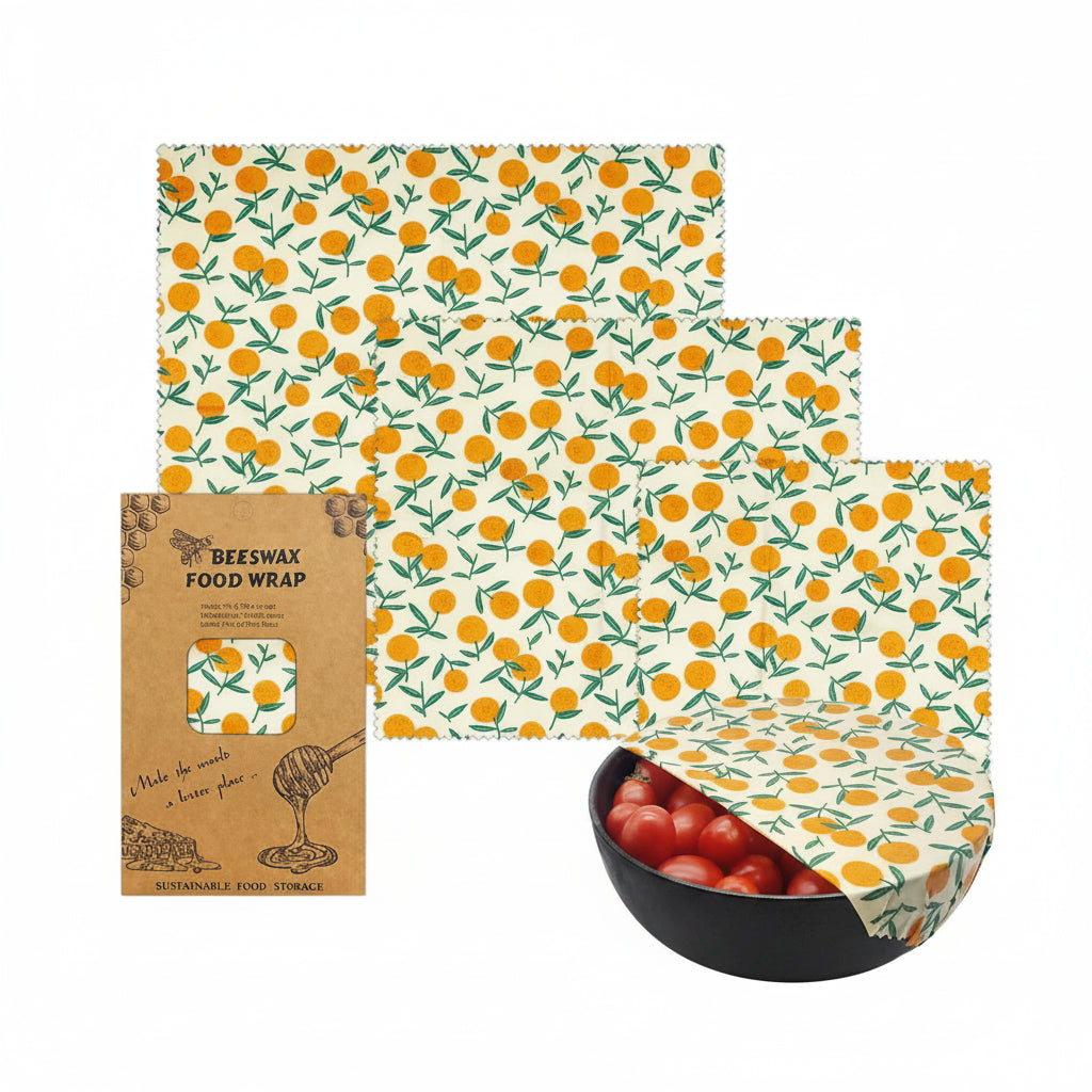 Beeswax food wrap set with orange floral pattern, showing three reusable wraps and packaging, one covering a bowl of tomatoes