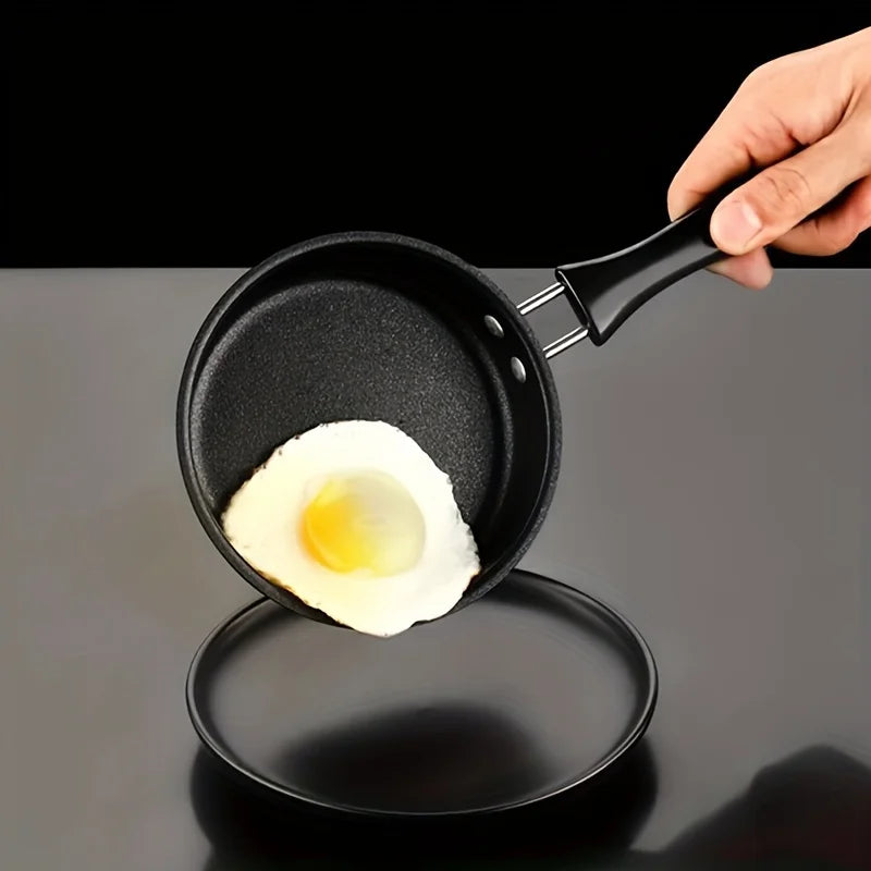 Black speckled cast iron skillet with black handle containing a fried egg with bright orange yolk on dark background.