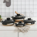 Black earthenware casserole pots with natural clay bases and wooden handles, displayed with lids and beige cloth napkin on wh
