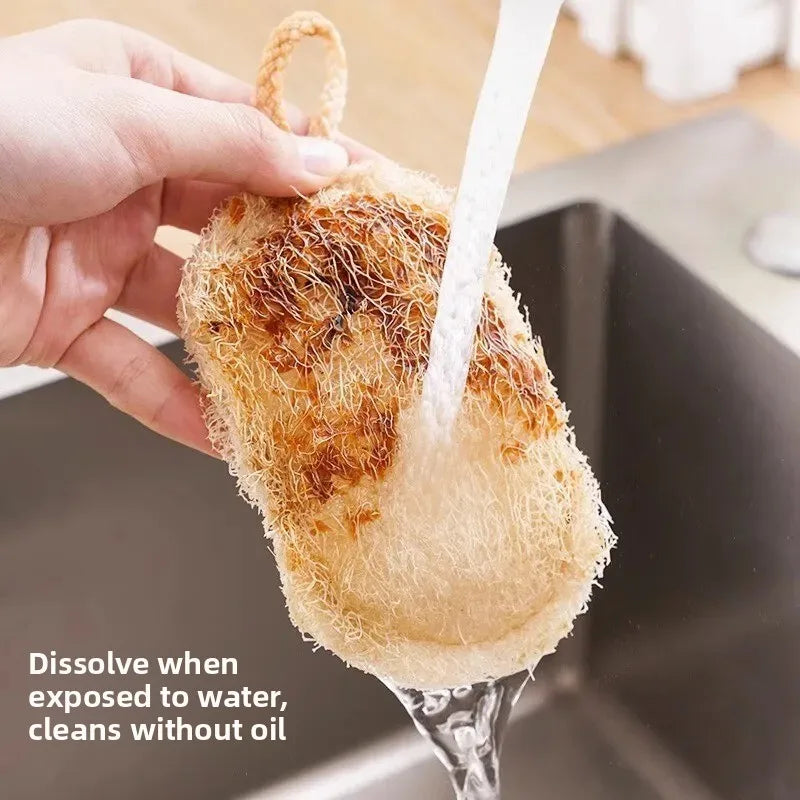 Natural loofah dish scrubber being rinsed under water in a sink, demonstrating its dissolving and oil-free cleaning propertie