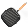 Cast iron square grill pan with ridged cooking surface, wooden handle with metal band, and drip spout for easy pouring.