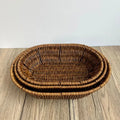 Hand-woven rattan bread basket with natural tan finish, nested stacking design, displayed on wooden surface