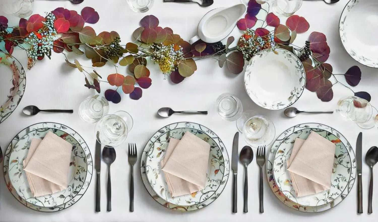 Elegant table setting with natural cotton linen napkins on floral plates, complemented by autumn foliage centerpiece and form