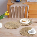 Handwoven rattan round placemats on wooden table with white dinnerware and yellow flowers, showcasing natural eco-friendly ki