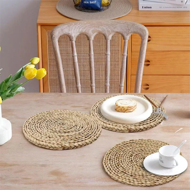 Handwoven rattan round placemats on wooden table with white dinnerware and yellow flowers, showcasing natural eco-friendly ki