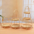 Three natural bamboo tiered baskets with arched handles in small, medium, and large sizes displayed on wooden floor.