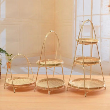 Three natural bamboo tiered baskets with arched handles in small, medium, and large sizes displayed on wooden floor.