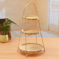 Three-tiered bamboo basket stand with natural woven baskets, metal frame, and carrying handle on wooden floor with plant and 