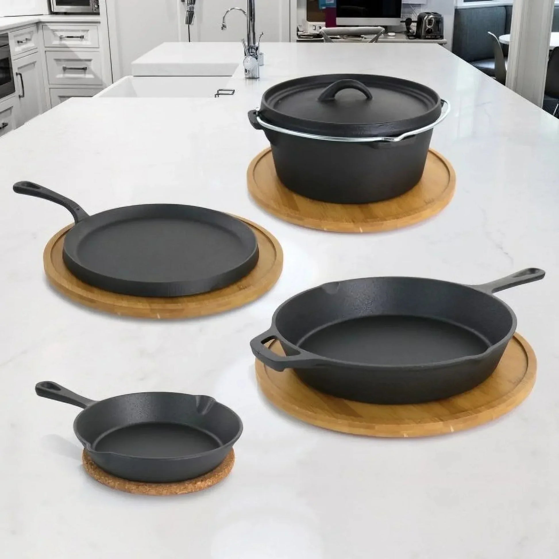 5-piece cast iron cookware set displayed on marble counter with wooden trivets, including skillets, Dutch oven, and griddle i