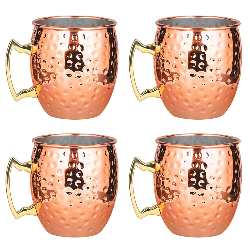 Set of four hammered copper Moscow Mule mugs with brass handles and stainless steel linings, featuring textured finish.