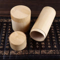 Three handcrafted bamboo tea storage canisters with lids displayed on decorative black surface with gold Asian characters.