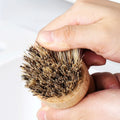 Natural wooden dish brush with organic coconut fibre bristles held in hand, eco-friendly cleaning tool