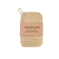 Natural loofah dish scrubber with rope loop, wrapped in kraft paper band with Chinese and English text labeling.