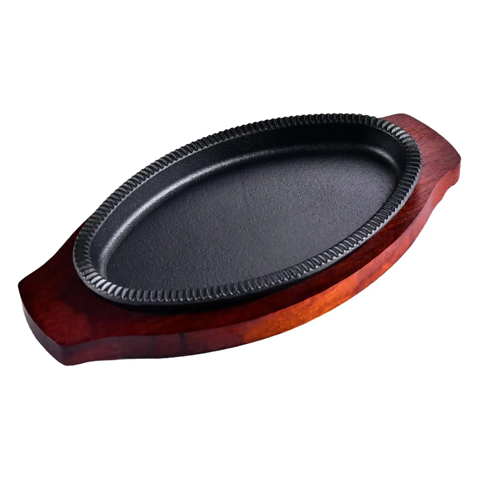 Cast iron oval griddle pan on wooden serving board with decorative rim, dark cooking surface visible.
