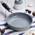 GraniteStone Fusion fry pan with gray granite non-stick coating, black handle, displayed on striped kitchen towel with decora