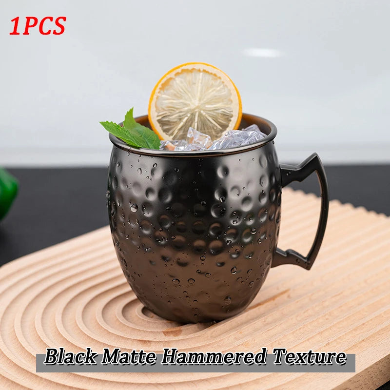 Black matte hammered copper mug with ice, lemon slice, and mint garnish on wooden coaster