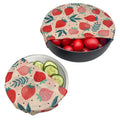 Reusable beeswax food wraps in strawberry print covering bowls of tomatoes and cucumbers, eco-friendly kitchen storage soluti
