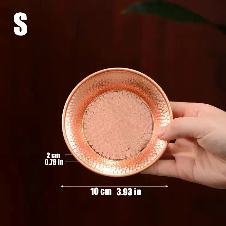 Small copper serving plate with hammered texture held in hand, showing 10cm diameter and 2cm rim height, artisanal design.
