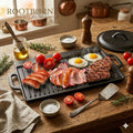 Cast iron dual-sided griddle with cooked meats, eggs, tomatoes, rosemary, salt, and oil on wooden table