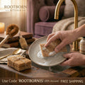 Hands washing natural bamboo and coconut fiber kitchen sponge in ceramic bowl with eco-friendly soap, wooden countertop setti